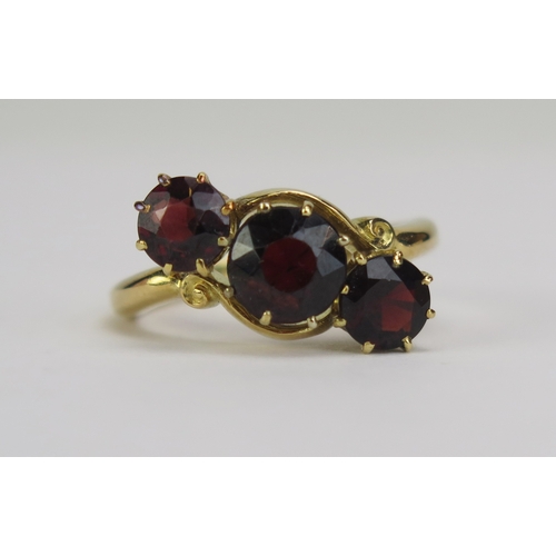 68 - An Antique Garnet Three Stone Crossover Ring, the 6.7mm central stone shouldered by two 5.48mm, the ... 