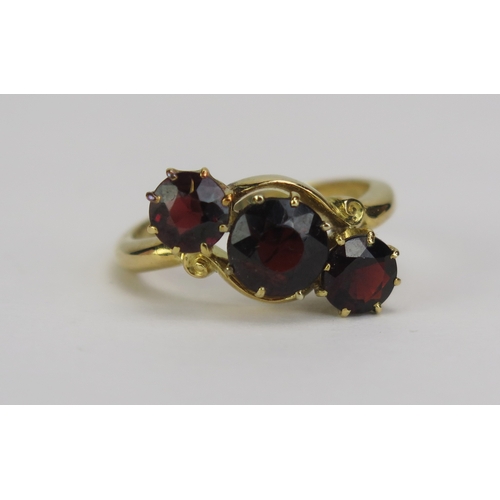 68 - An Antique Garnet Three Stone Crossover Ring, the 6.7mm central stone shouldered by two 5.48mm, the ... 