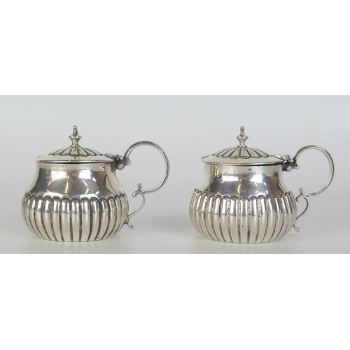 681 - A pair of matched lidded mustard pots, various makers and dates, of circular form with half reeded d... 