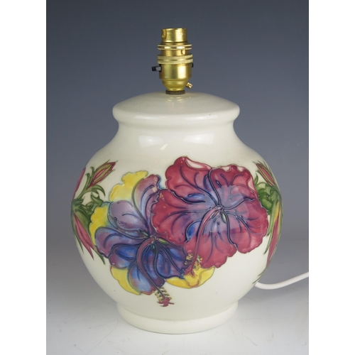 1039 - A Moorcroft pottery table lamp of globular form with Hibiscus decoration to an ivory ground, overall... 