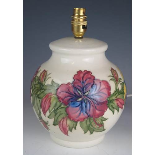 1039 - A Moorcroft pottery table lamp of globular form with Hibiscus decoration to an ivory ground, overall... 