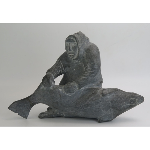 1043 - An Inuit carved hardstone figure group of an Eskimo with a baby killer whale, inscribed to the base ... 