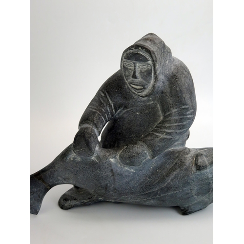 1043 - An Inuit carved hardstone figure group of an Eskimo with a baby killer whale, inscribed to the base ... 