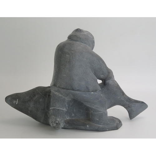 1043 - An Inuit carved hardstone figure group of an Eskimo with a baby killer whale, inscribed to the base ... 