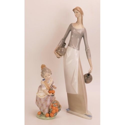 1051 - A Nao porcelain figure of a female water carrier holding two pitchers, 39cm high, together with a Ll... 