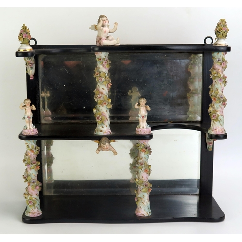 1061 - A 19th century ebonised and porcelain set of shelves with mirror panelled back, the porcelain column... 