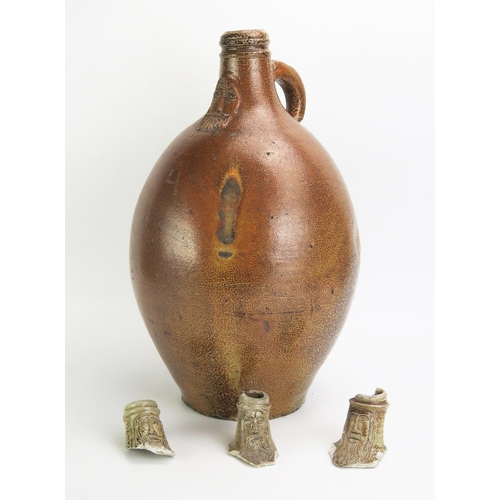 1068 - A large German stoneware Bellarmine jug, 43cm high, together with three  bellarmine jug necks. (4)