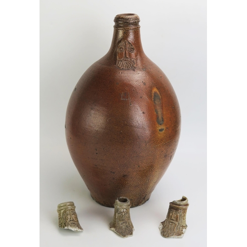 1068 - A large German stoneware Bellarmine jug, 43cm high, together with three  bellarmine jug necks. (4)