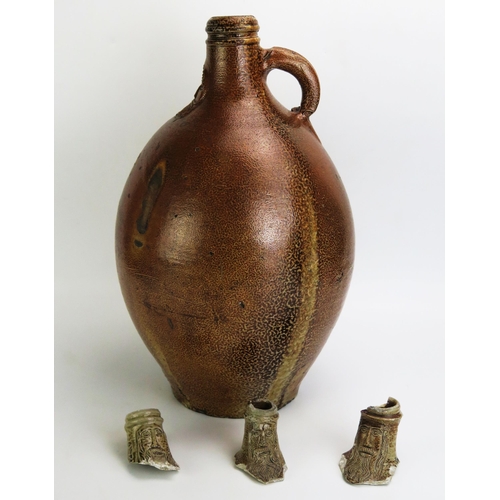 1068 - A large German stoneware Bellarmine jug, 43cm high, together with three  bellarmine jug necks. (4)