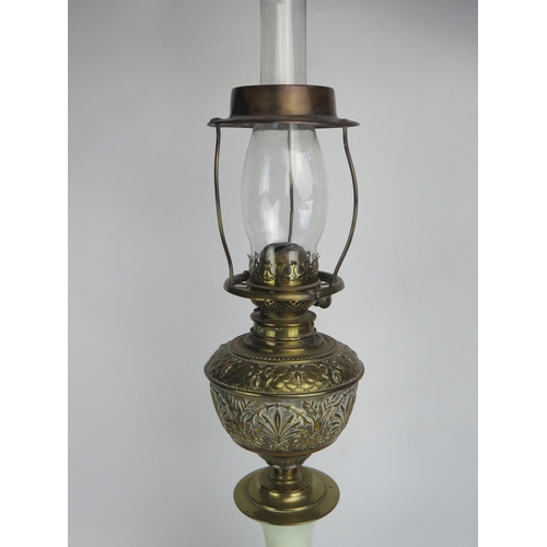 1389 - A Victorian brass and glass oil lamp, with embossed brass reservoir mounted on a green glass and flo... 