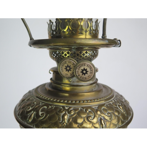 1389 - A Victorian brass and glass oil lamp, with embossed brass reservoir mounted on a green glass and flo... 