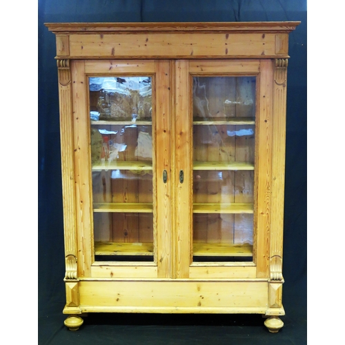 1602 - A large Victorian stripped pine bookcase, with a moulded cornice above a pair of glazed panelled doo... 