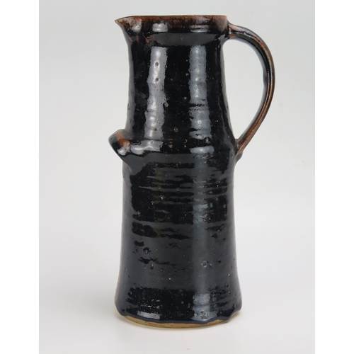 1158 - A large pottery jug, possibly by Dora Lunn, of cylindrical outline with tenmoku glaze, 31cm high.