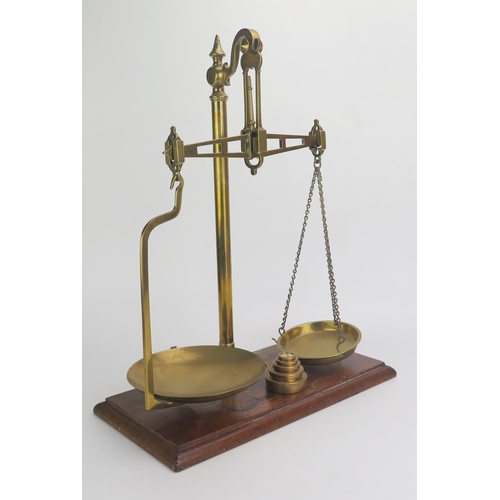 1180 - A pair of lacquered brass balance scales, mounted on a rectangular polished wood base, with five gra... 