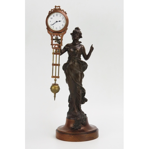 1181 - A bronzed metal mystery timepiece, modelled as a young lady standing in a flowing dress holding alof... 