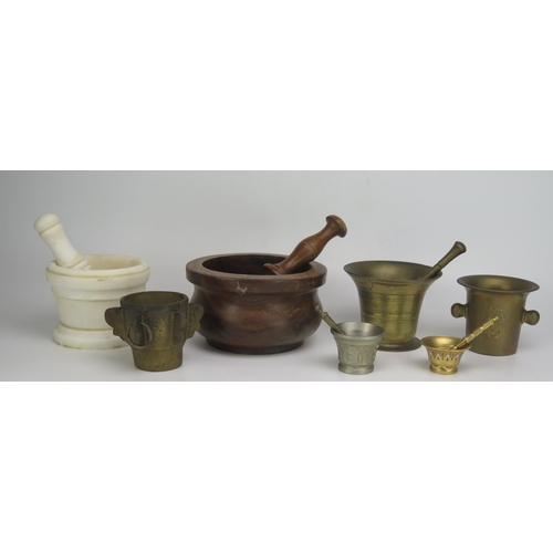 1322 - A turned wood pestle and mortar, three small brass mortars and an alabaster pestle and mortar.