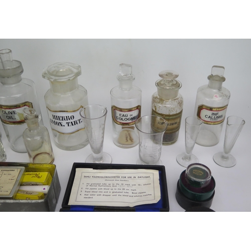 1327 - A collection of clear glass pharmaceutical bottles and stoppers, measuring jars, syringe etc.