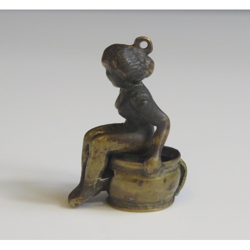 1621 - A novelty bronze cigar cutter in the form of a nude lady seated on a chamber pot, 3.5cm high.