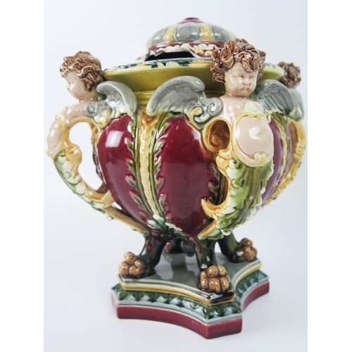 1643 - A German majolica vase and cover, the bowl with floral decoration supported by four cherubs, raised ... 