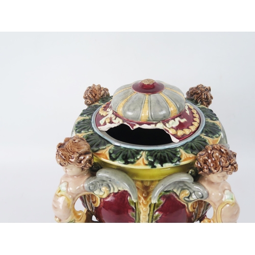 1643 - A German majolica vase and cover, the bowl with floral decoration supported by four cherubs, raised ... 