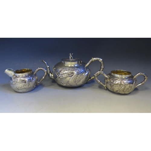 601 - A Chinese silver three-piece tea service by Wang Hing & Co, Hong Kong, of cylindrical outline with e... 