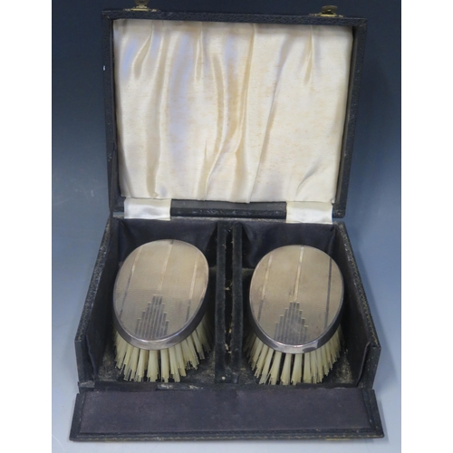 669 - A pair of Elizabeth II silver backed brushes, maker W I Broadway & Co, Birmingham, 1964, contained i... 