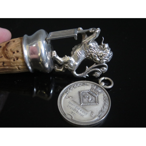 752 - A white metal bottle stopper modelled as a rampant lion, together with a silver cricket medallion. (... 