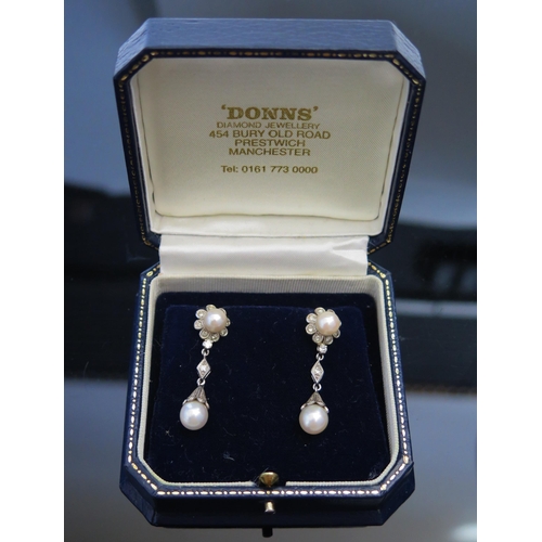 294 - A Pair of Cultured Pearl and Diamond Pendant Earrings in a precious white metal setting, 38mm long, ... 