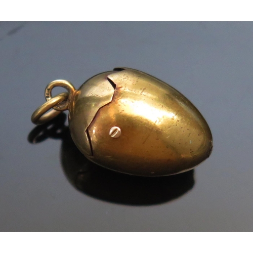 296 - A Precious Yellow Metal Articulated Egg Pendant with spring loaded mechanism opening to reveal a chi... 