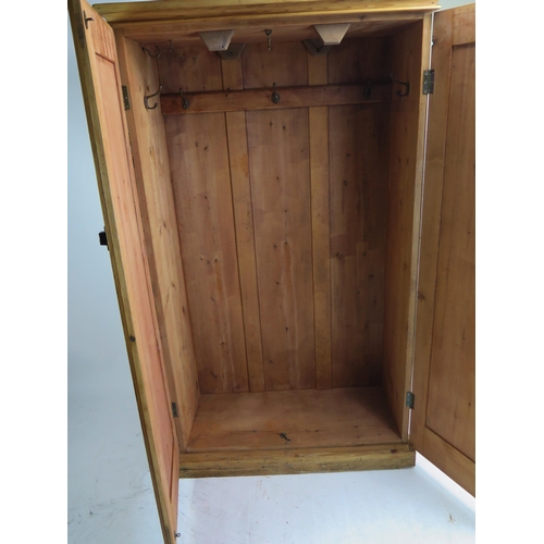 1707 - A Victorian stripped pine cupboard, the top with a moulded cornice above a pair of arched moulded pa... 