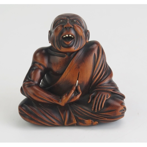 153 - A Carved hardwood netsuke of a professional sneezer seated with his right hand raised, holding a tic... 