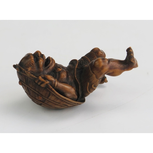 154 - A Japanese carved boxwood netsuke in the form of an oni carrying a shield on his back, signed, 5.5cm... 