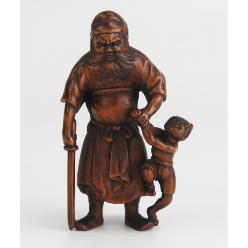 157 - A Japanese carved okimono of Shoki the demon queller, the standing figure with oni in one hand and a... 