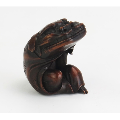 160 - A Japanese carved hardwood netsuke depicting a man putting on a Dragons head costume, unsigned, 5cm ... 