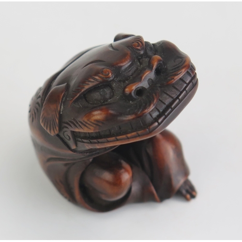 160 - A Japanese carved hardwood netsuke depicting a man putting on a Dragons head costume, unsigned, 5cm ... 