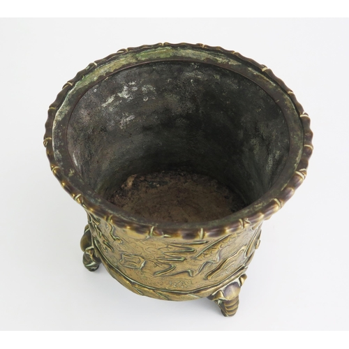 164 - An Antique Chinese cast bronze pot of cylindrical tapering outline, with simulated bamboo rim, the s... 