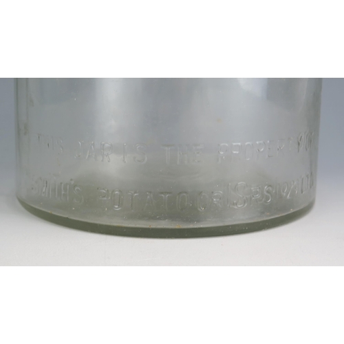 173 - A clear glass advertising jar and cover for 'Smiths Crisps' of cylindrical outline, with domed cover... 