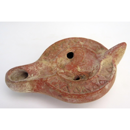 205 - A Roman terracotta oil lamp with a flattened base, smooth side walls, grooved perimeter, and a reces... 