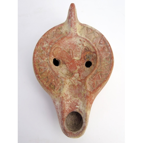 205 - A Roman terracotta oil lamp with a flattened base, smooth side walls, grooved perimeter, and a reces... 