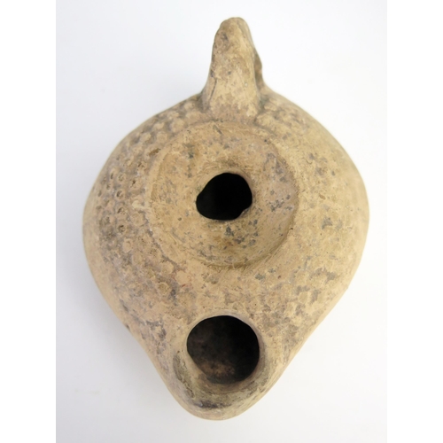 205 - A Roman terracotta oil lamp with a flattened base, smooth side walls, grooved perimeter, and a reces... 