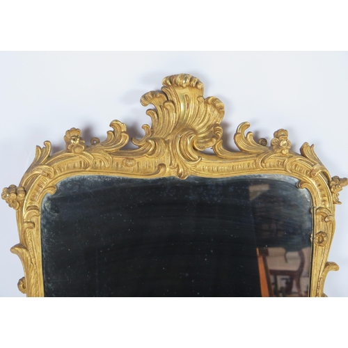 361 - A carved gilt wood wall mirror, the rectangular mirror plate enclosed by an arched frame with scroll... 