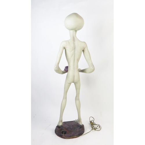 1033 - Life Size Alien Resin Figure holding a lamp (wired and working) standing on a purple rock base, 49.5... 