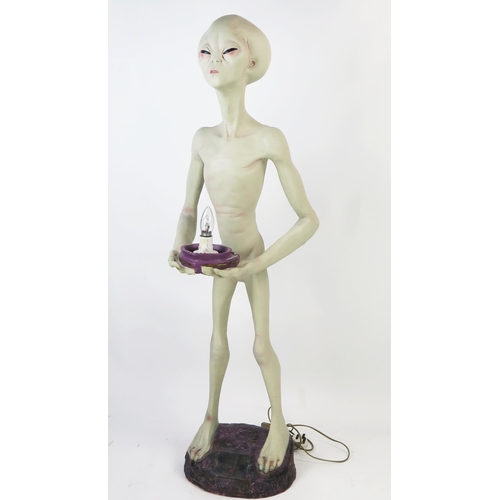 1033 - Life Size Alien Resin Figure holding a lamp (wired and working) standing on a purple rock base, 49.5... 