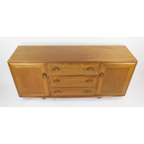 1138 - An Ercol Mid Elm Sideboard with three central drawers and cutlery tray flanked by a cupboard to each... 