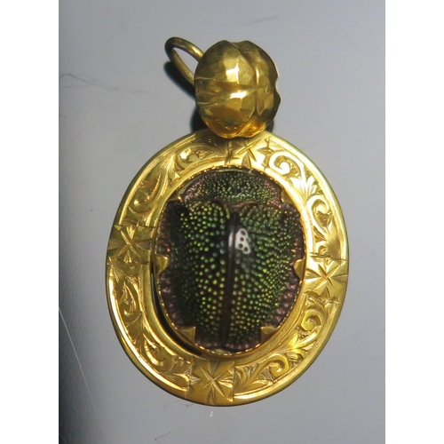 122 - An Antique Scarab Beetle Pendant in a precious yellow metal setting with chased scrolling foliate bo... 