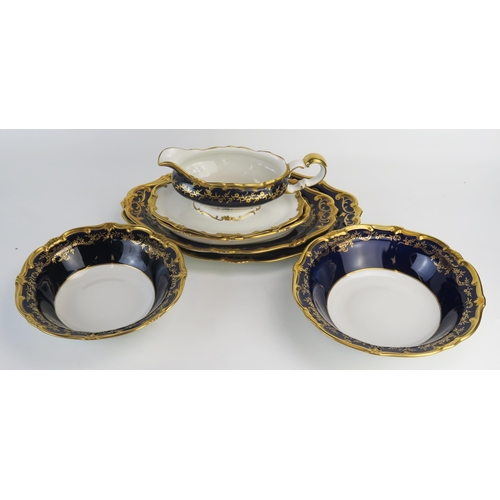 1101 - A German porcelain part dinner service, with cobalt blue border with gilded foliate and scroll decor... 