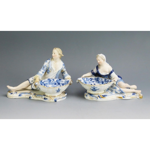 1106 - A pair of Meissen porcelain table salts in the form of twin-handled bowls held by reclining gallant ... 