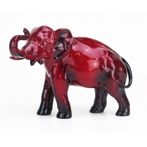 1129 - A Royal Doulton flambé model of an elephant, with raised trunk, 22cm long.