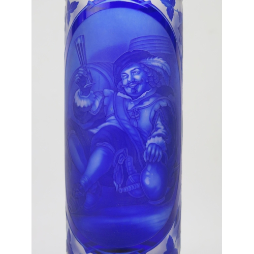 1184 - A Bohemian overlay blue glass vase, of cylindrical form, the central panel depicting drinking cavali... 