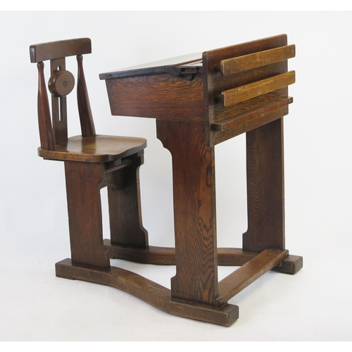 1512 - A late Victorian elm and beech school desk, the sloping hinged top, with pen tray and brass inkwell,... 